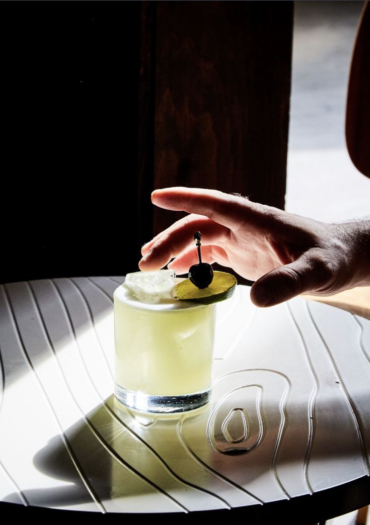 a person reaching for a drink on a table with a shadow from the sun coming in