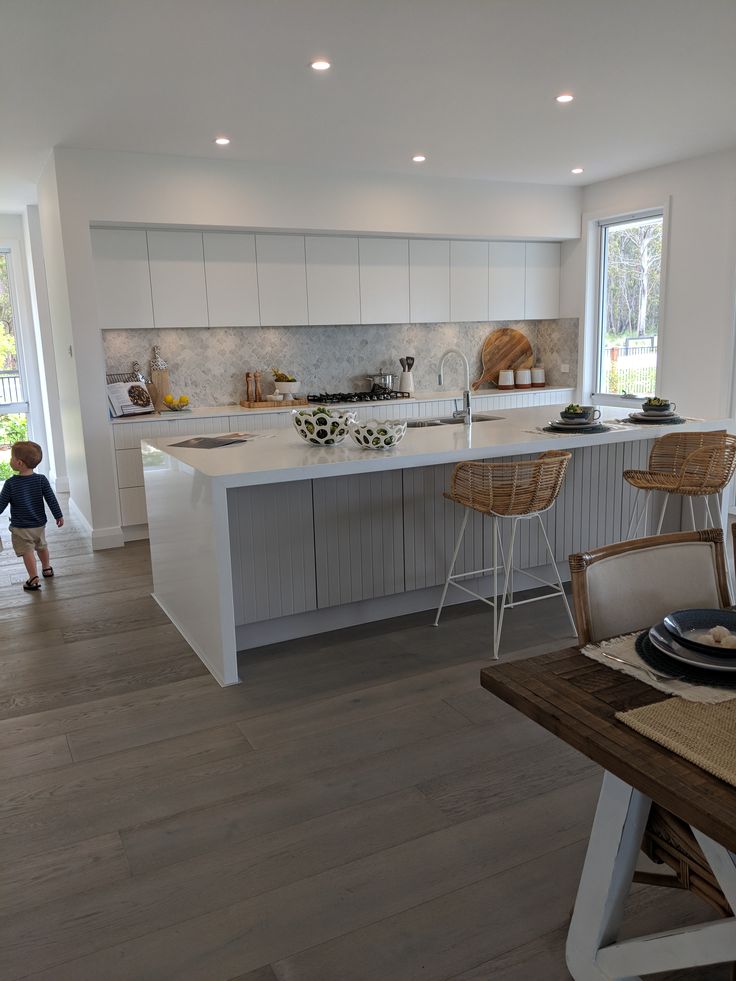 a little boy standing in the middle of a kitchen next to a table and chairs