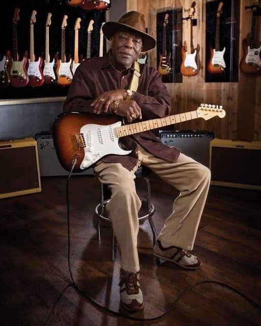 a man sitting in a chair with an electric guitar