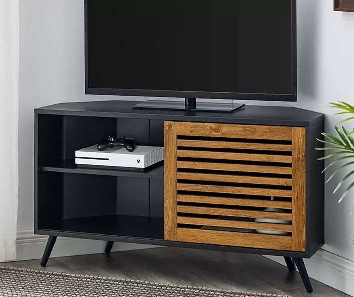 a flat screen tv sitting on top of a wooden entertainment center next to a potted plant