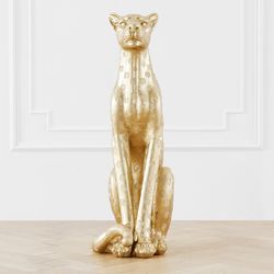 a golden cat statue sitting on top of a wooden table next to a white wall