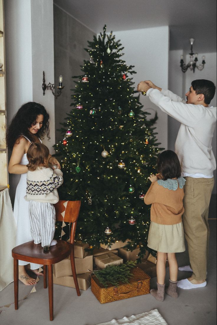 a man and two children standing in front of a christmas tree