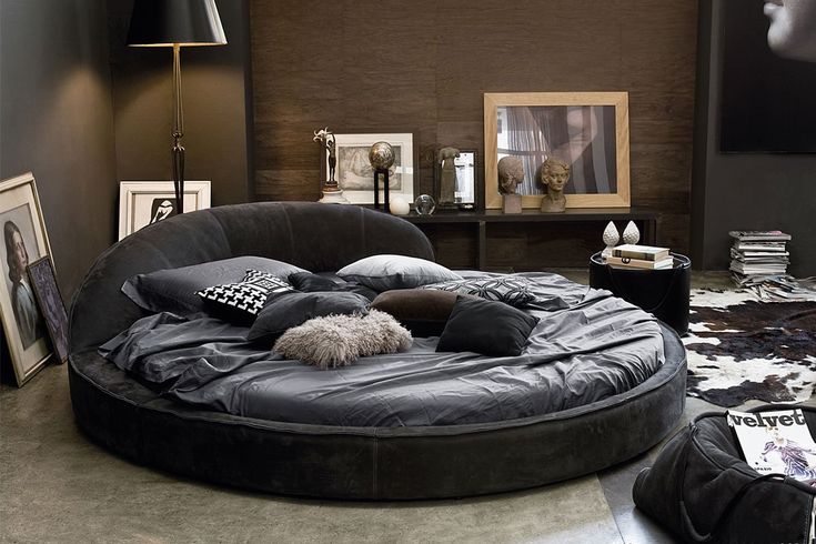 a black round bed in a living room with pictures on the wall and flooring