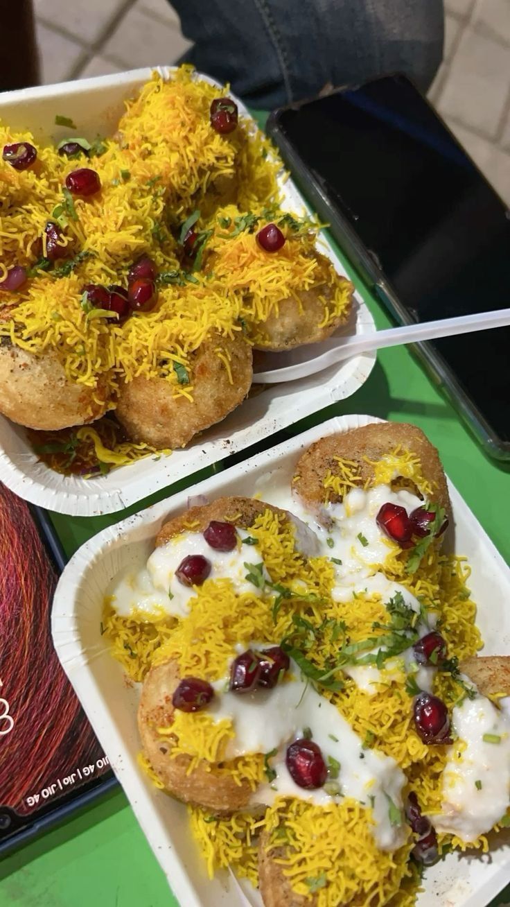 two plates with food on them sitting on a table next to a book and phone