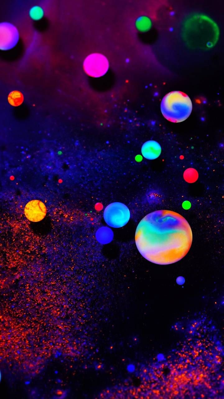 an array of different colored bubbles on a black surface with multicolored dots in the background