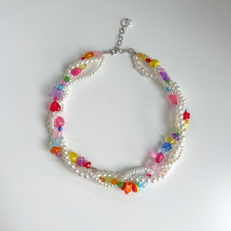 a multi - colored bracelet with beads and charms on a white surface, the bead is attached to a silver chain