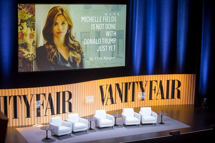 a stage with chairs and a large screen behind it that says,'vanity fair '