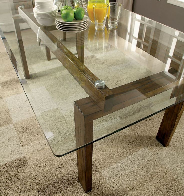 a glass table with wooden legs in a living room filled with furniture and plates on the floor