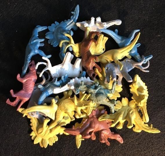 a pile of small plastic dinosaurs sitting on top of a carpet