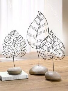 three metal leaf sculptures sitting on top of a wooden table next to a bookend