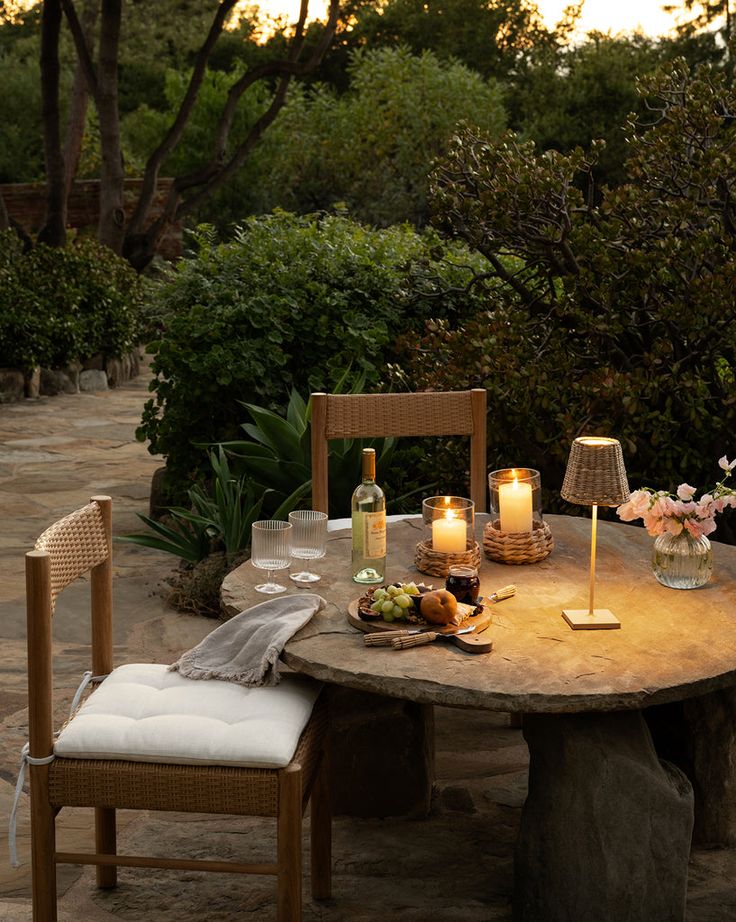 the table is set with candles and plates of food on it, along with two chairs