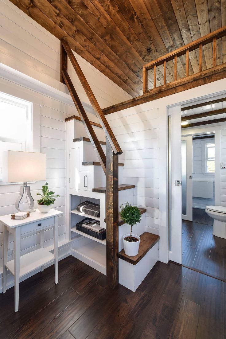 a white room with wood floors and a wooden staircase leading to the upper floor area