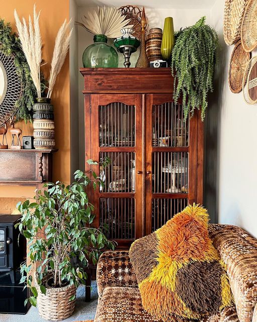 a living room filled with lots of furniture and plants in front of a wooden cabinet