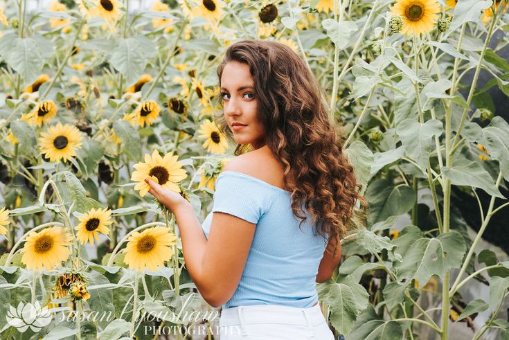 a girl standing in front of a field of sunflowers