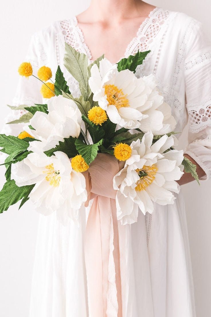 a woman holding a bouquet of white and yellow flowers