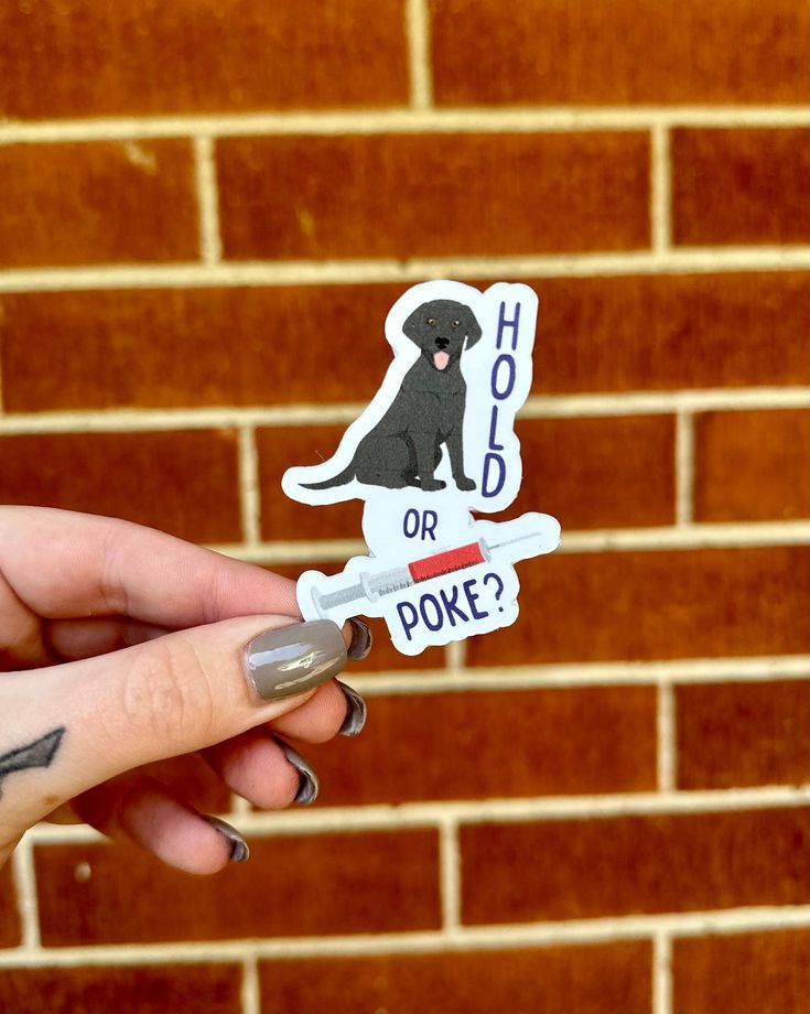 a hand holding a sticker with a dog on it that says hold or poke?