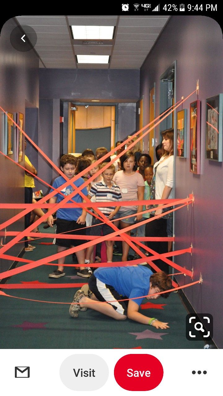 a group of children standing in a hallway with red tape on the floor and walls