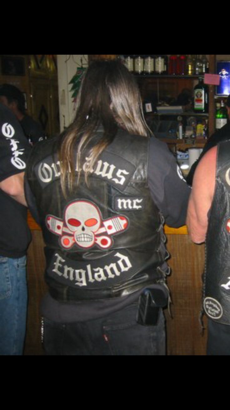 two men wearing leather vests with skulls and bones on them, standing next to each other