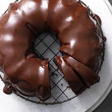 a chocolate bundt cake sitting on top of a white plate next to a knife