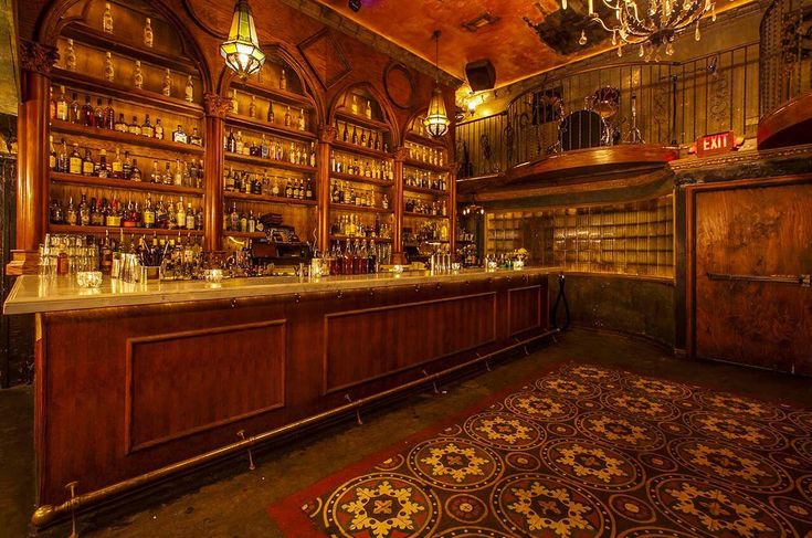 an old fashioned bar with wooden shelves and chandeliers