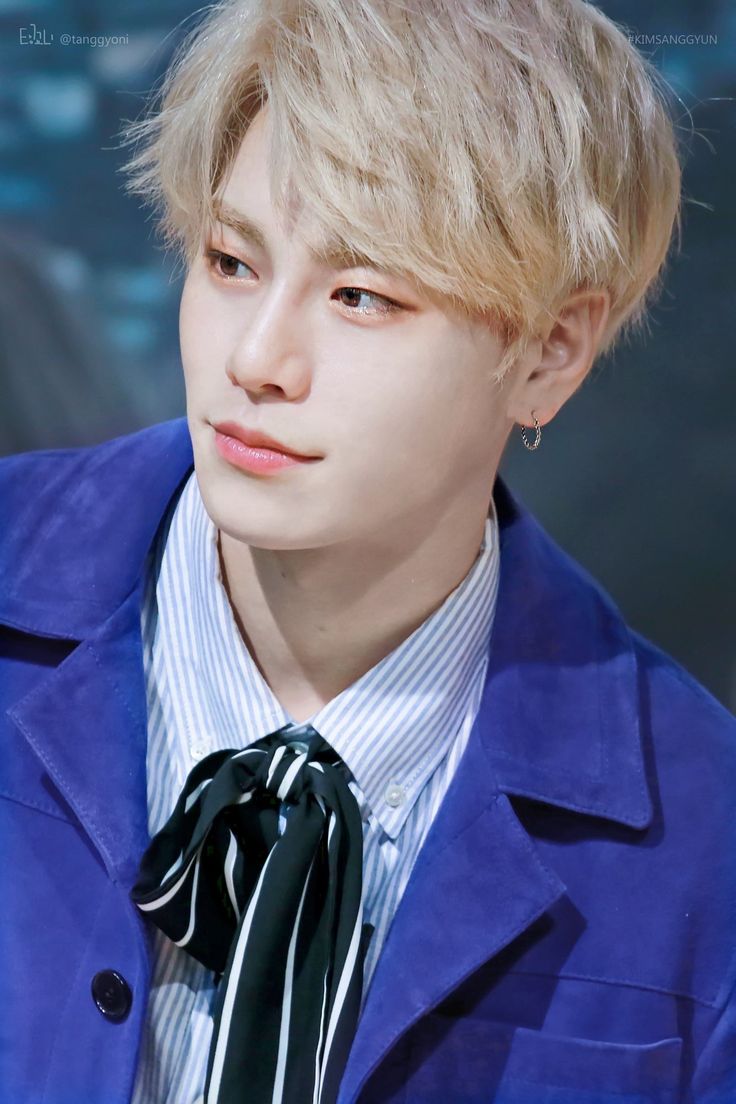 a young man with blonde hair wearing a blue jacket and tie