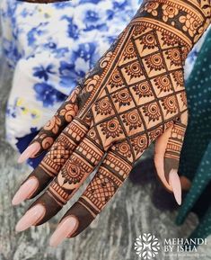 a woman's hand with henna tattoos on it and her hands showing the intricate design