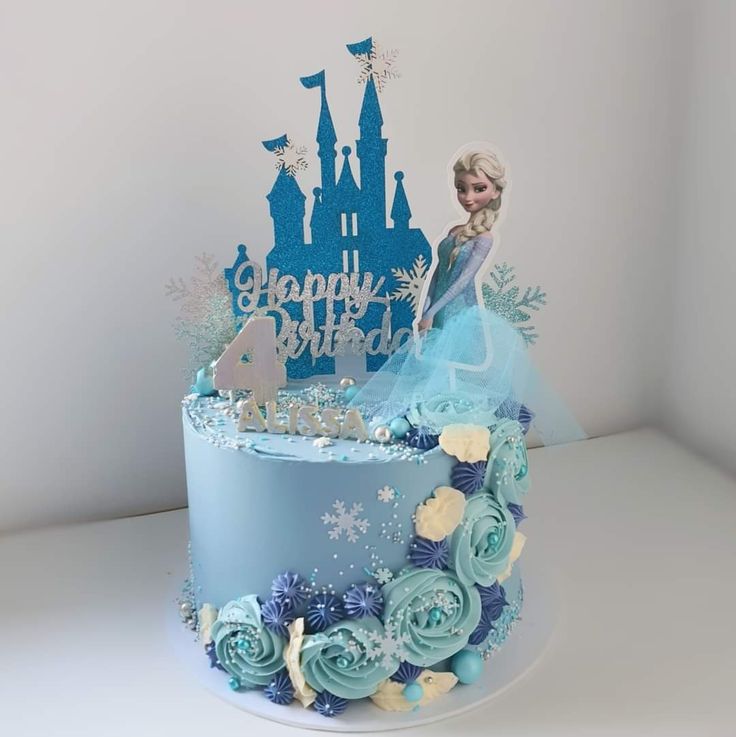 a frozen princess cake with blue frosting and flowers on top, sitting in front of a white wall