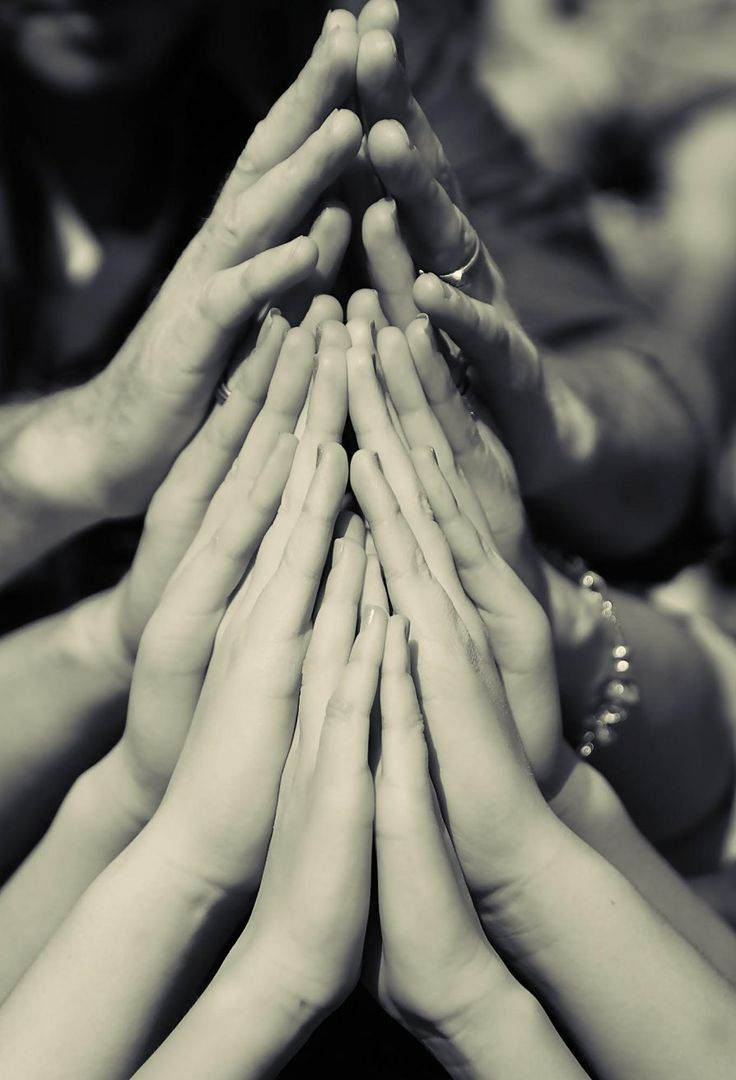 many people are holding their hands together to form a pyramid in black and white photo