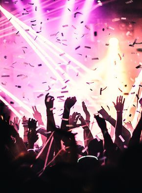 a crowd of people at a concert with confetti in the air and lights above them