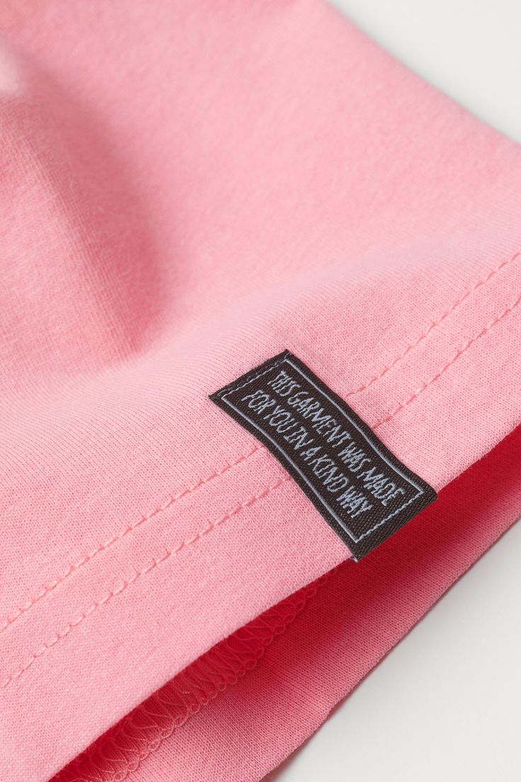 a pink shirt with a black label on it