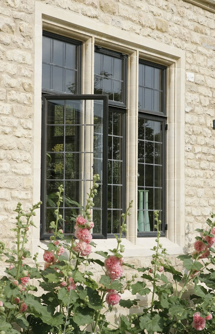 the window is open and there are pink flowers in front of it