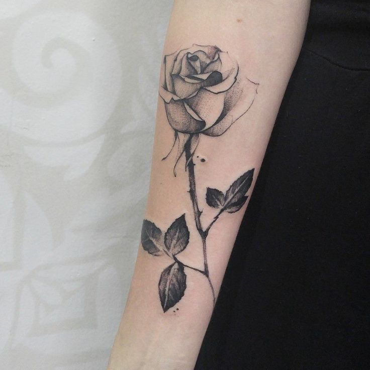 a black and white rose tattoo on the arm