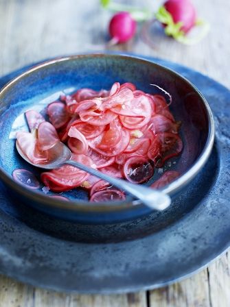 a blue bowl filled with red onions on top of a wooden table