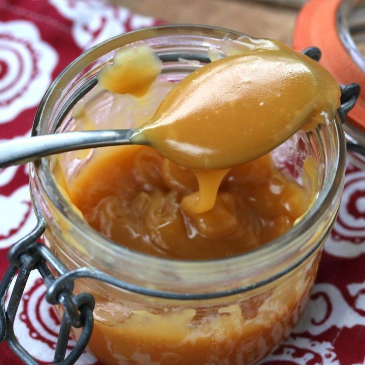 a spoon full of caramel sauce on top of a jar