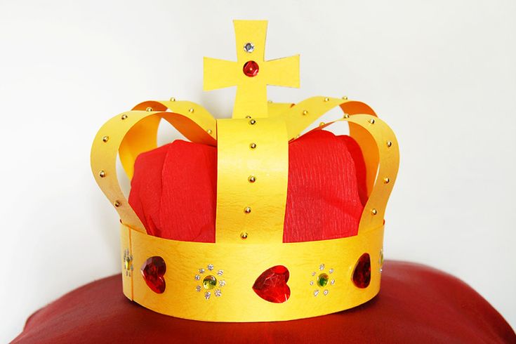 a yellow crown sitting on top of a red pillow