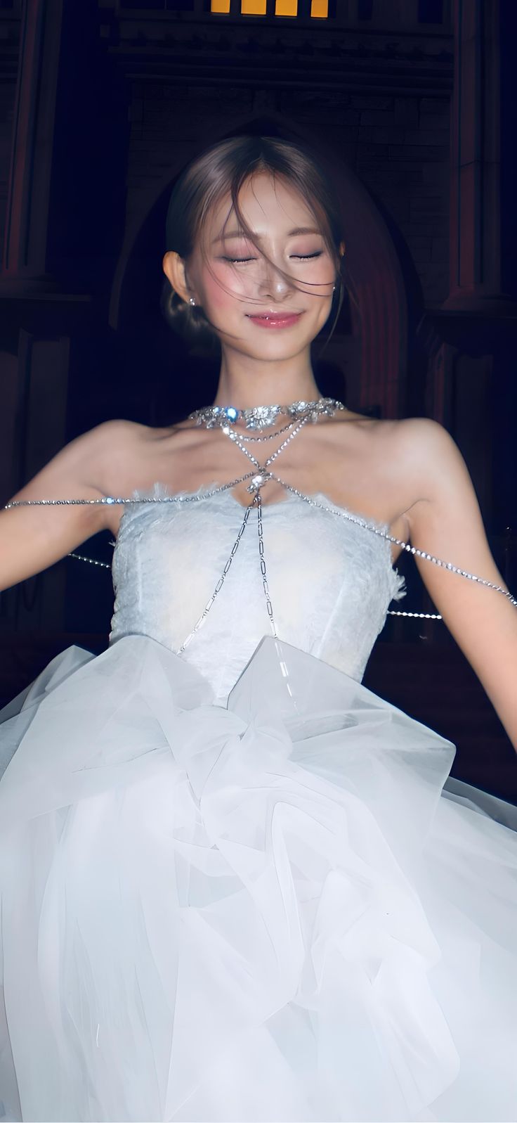 a woman in a white dress with pearls on her neck and hands behind her back