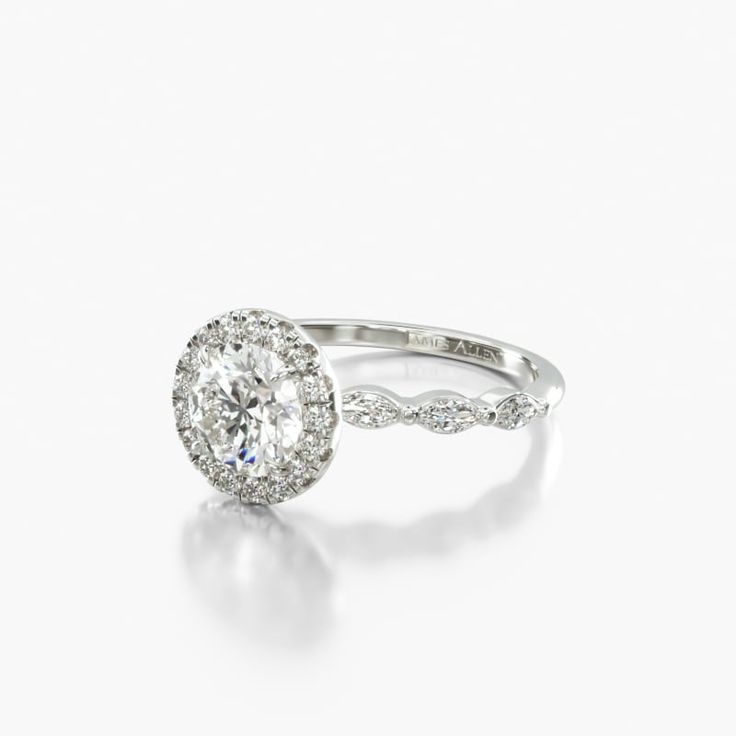 a white gold ring with an oval cut diamond in the center and pave set shoulders