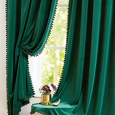 a green curtain with scalloped edges and beaded trim hangs in front of a window