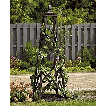 a wooden tower with ivy growing on it's sides in the grass next to a fence