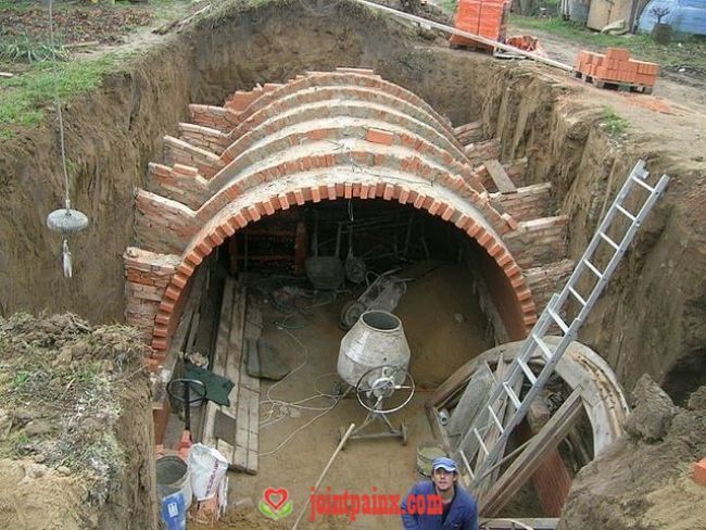 two men are standing in the middle of a tunnel that is being built into the ground