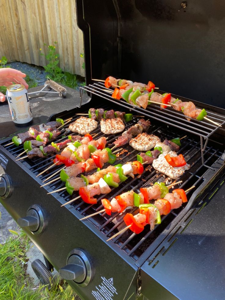 several skewers of meat and vegetables cooking on an outdoor grill