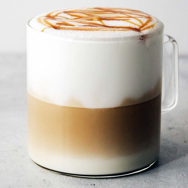 there is a cup of coffee with some liquid in the foam on top and caramel swirl