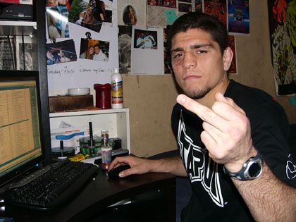 a man sitting in front of a computer pointing at the camera with his finger up