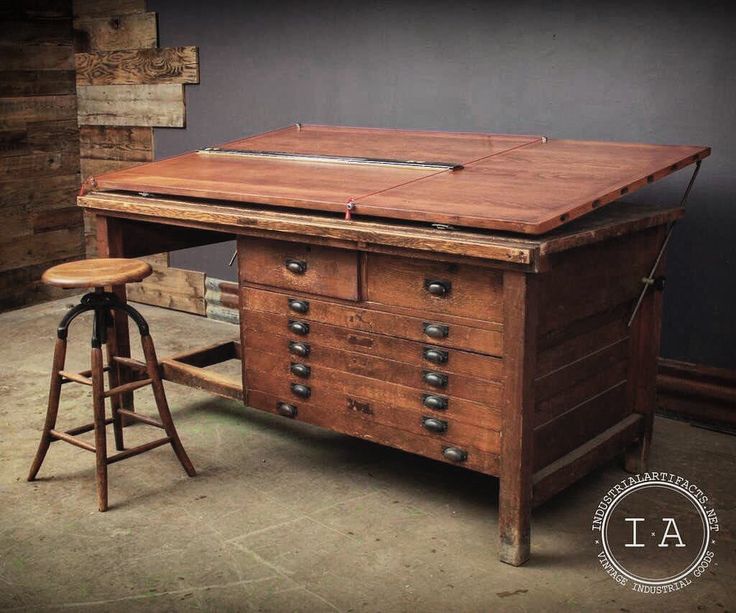 an old wooden desk with two stools in front of it and a table top on the other side