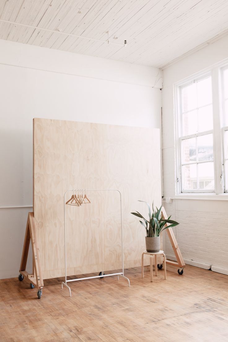 a room with two planters on the floor and a large wooden board in front of it