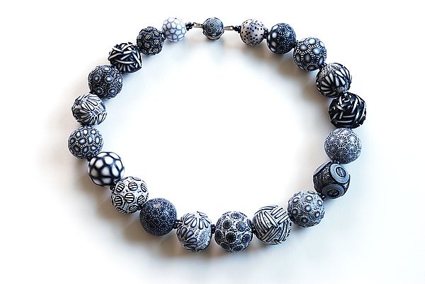 a beaded bracelet with black and white beads on a white background, in the shape of an ornament