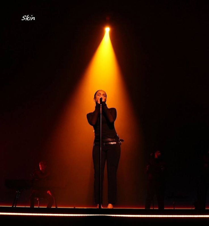 a woman standing on top of a stage holding a microphone in front of her face