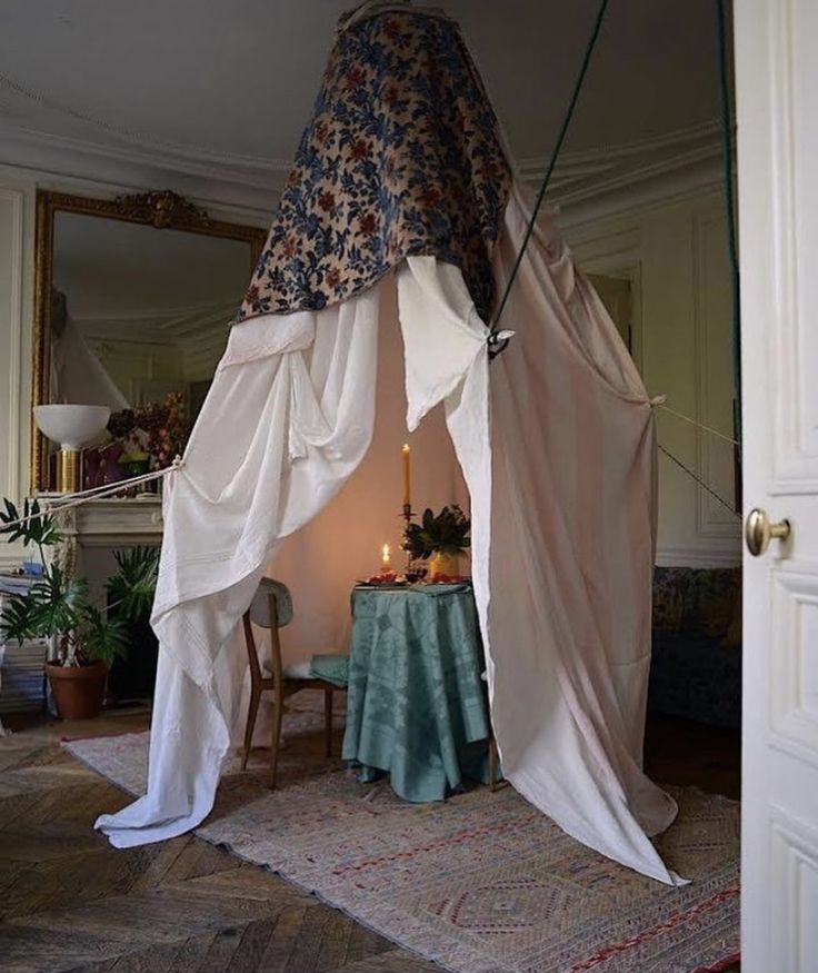 a room with a tent and table in the corner, next to a door that has a mirror on it