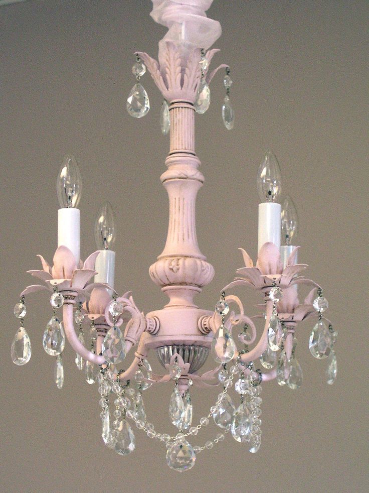 a white chandelier hanging from the ceiling with crystal drops on it's arms