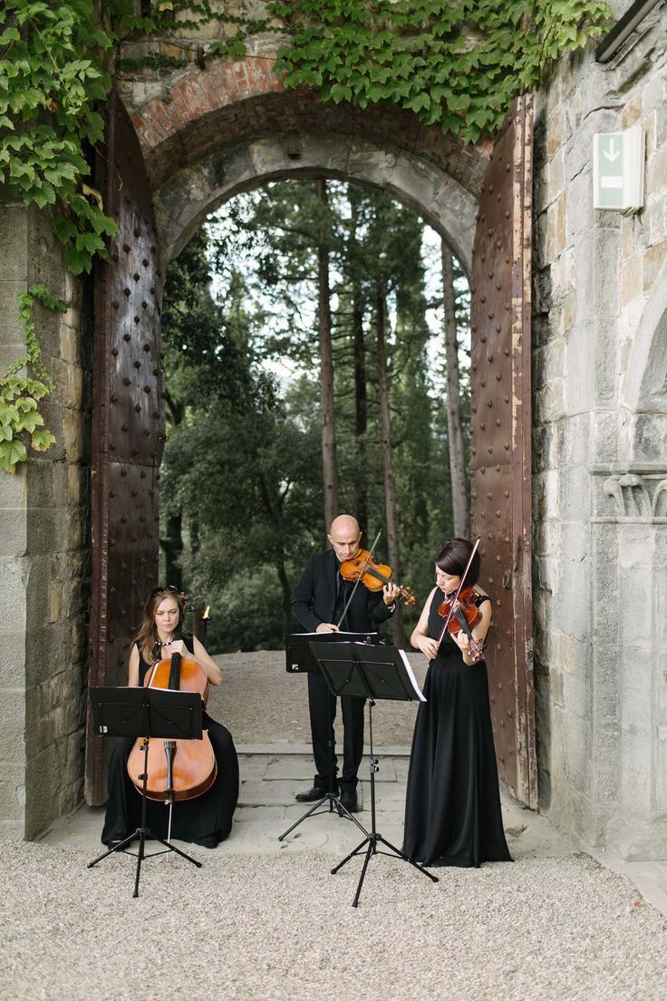 three people are playing music in an archway